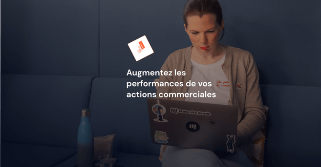 Photo de face d'une jeune femme assise dans son canapé avec son ordinateur sur les genoux.