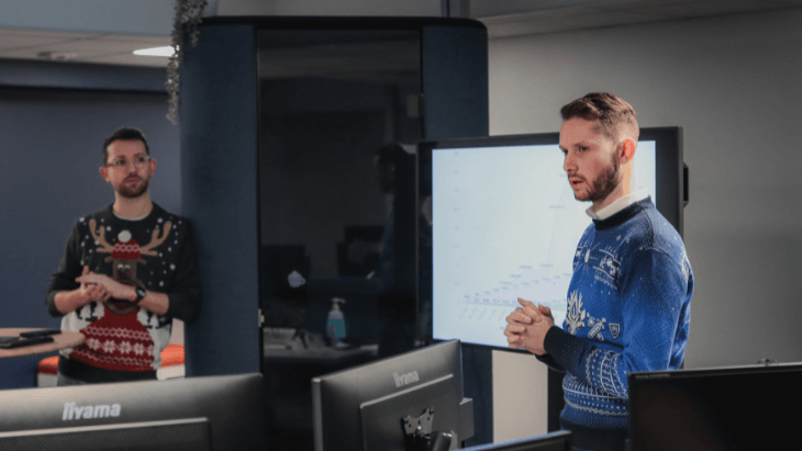 simon et justin en pull de noël qui présentent des chiffres sur une télévision