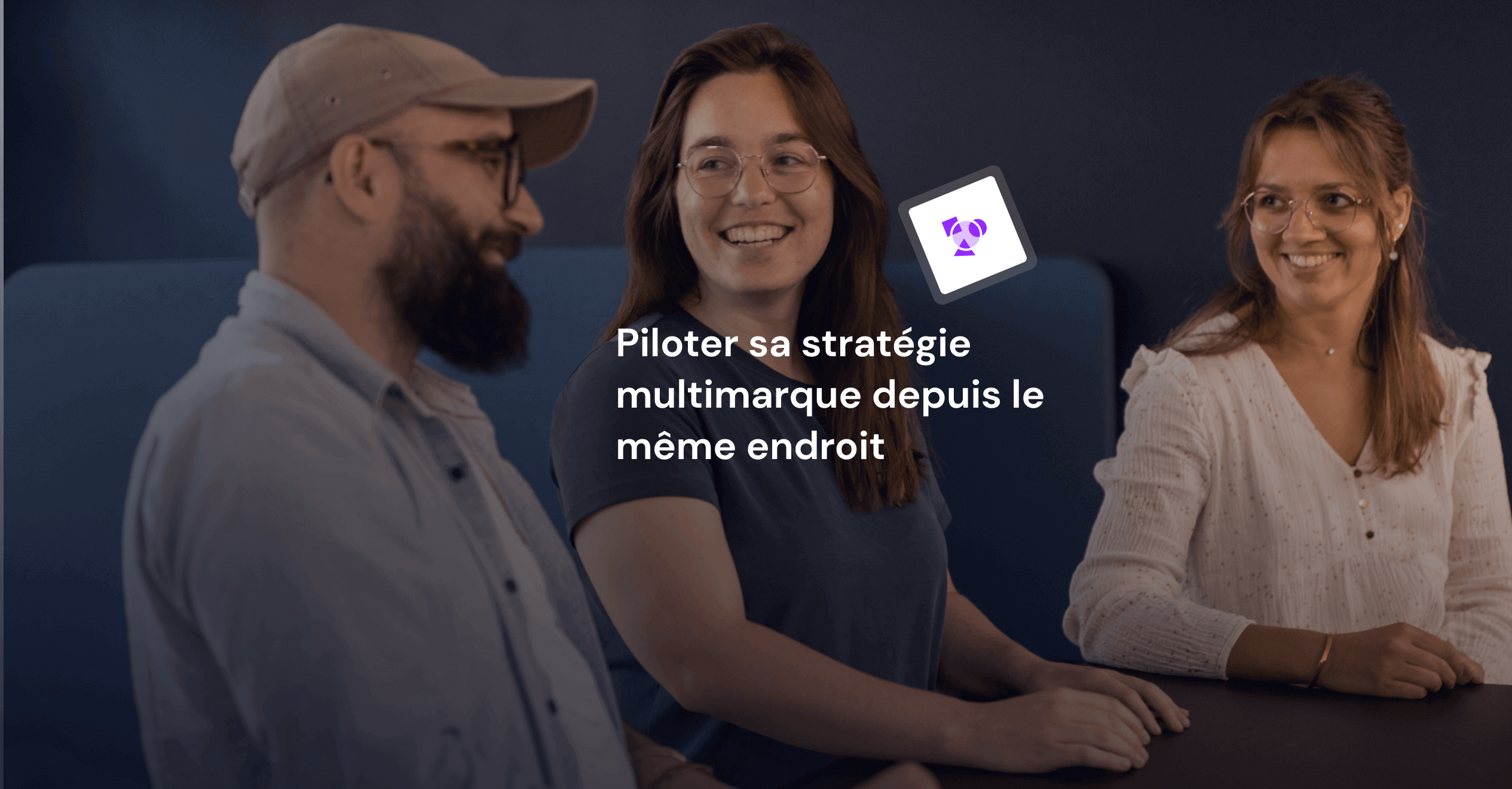 Photo d'un homme et de deux femmes en train de discuter et de rire debout autour d'une table.