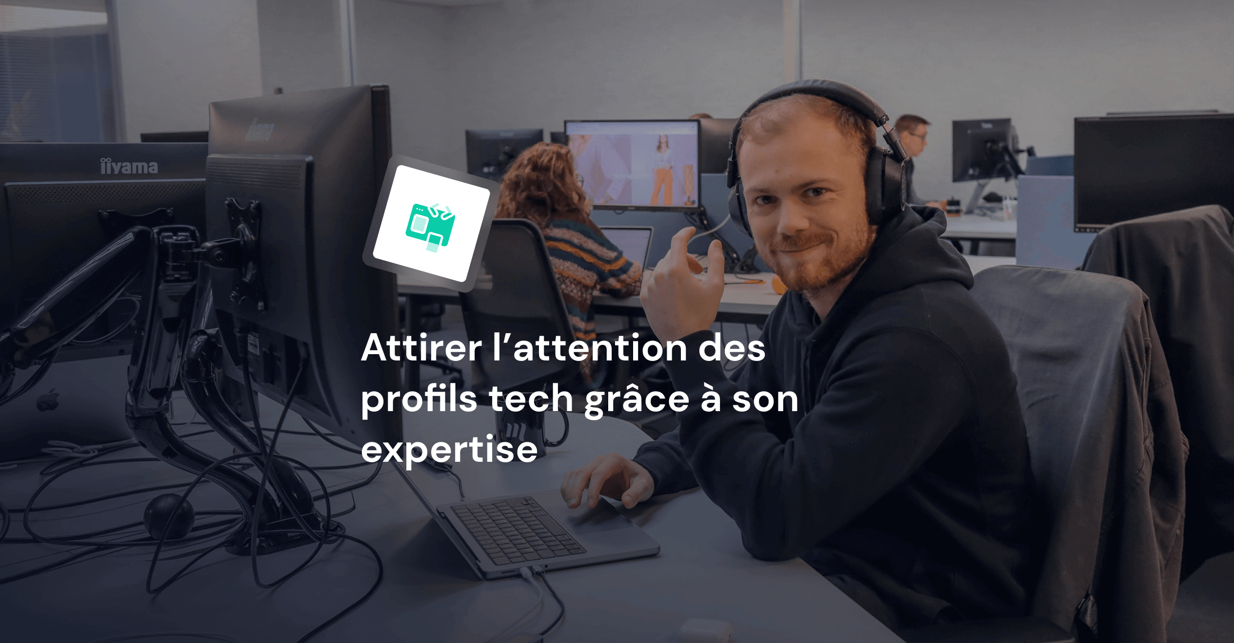 Jeune homme developpeur assis devant son poste de travail avec un casque bluetooth.